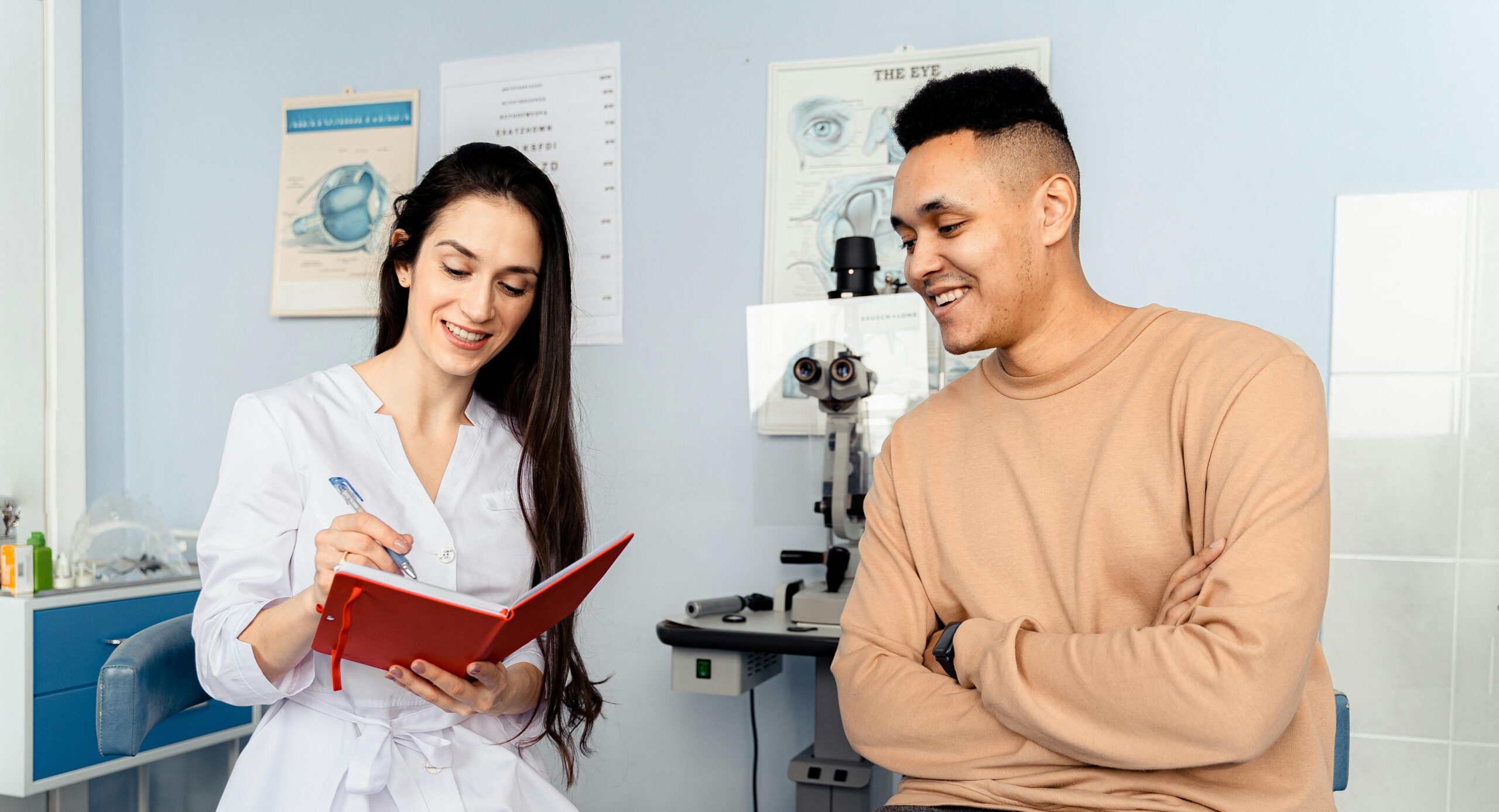 A male patient interacts with a female ophthalmologist in a clinic, showcasing a friendly consultation.